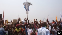 FILE - Supporters of Congo opposition leader Etienne Tshisekedi, rear, hold up a cross that symbolizes no third term for DRC President Joseph Kabila, during a political rally in Kinshasa, DRC, July 31, 2016.