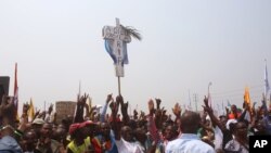 FILE - Supporters of Congo opposition leader Etienne Tshisekedi, rear, hold up a cross that symbolizes no third term for DRC President Joseph Kabila, during a political rally in Kinshasa, DRC, July 31, 2016.