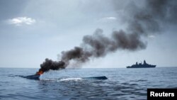 FILE - As part of the EU Naval Force Somalia, the German Frigate 'Hamburg' patrols after destroying two fishing boats (L) which were discovered floating keel side up in open waters off the coast of Somalia, August 15, 2011.