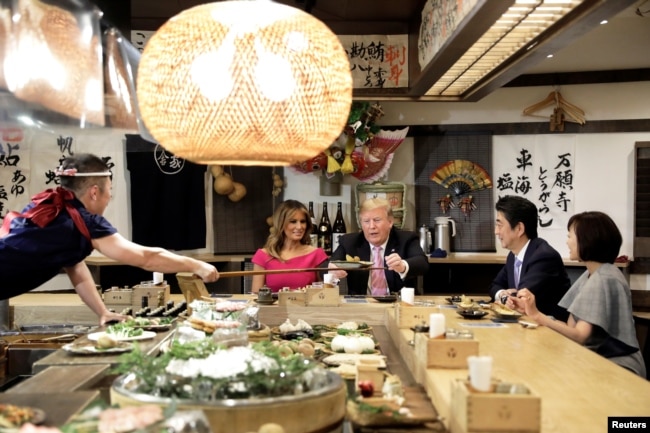 U.S. President Donald Trump, with first lady Melania Trump, receives a plate of food from a chef as they and Japanese Prime Minister Shinzo Abe and his wife Akie Abe have a couples dinner in Tokyo, May 26, 2019.