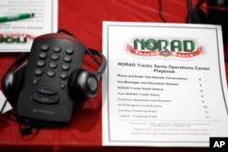 A playbook sits next to a telephone set up in the NORAD Tracks Santa center at Peterson Air Force Base, Monday, Dec. 23, 2019, in Colorado Springs, Colo. More than 1,500 volunteers will handle an estimated 140,000 telephone calls from children and their parents who will be checking on the wherabouts of Santa Claus on Christmas Eve. (AP Photo/David Zalubowski)