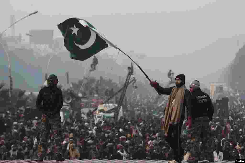 A supporter of Tahir-ul Qadri waves a Pakistani flag as he walks on a container on the third day of protests in Islamabad, Pakistan, January 16, 2013.