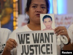 Seorang perempuan menampilkan foto putranya yang menjadi korban perang narkoba sambil membawa plakat dalam aksi protes melawan kebijakan "Perang Melawan Narkoba" Presiden Rodrigo Duterte di kota Quezon, Metro Manila, Filipina, 28 Agustus 2018.