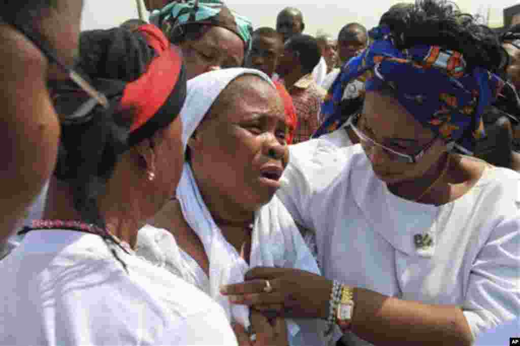 An Unidentified woman, centre, who lost her husband Mourns during a mass funeral of those killed in a Christmas Day bombing at a Catholic church in Madalla, Nigeria, on Wednesday, Feb. 1, 2012.