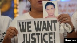 A woman displays a picture of her son, a drug war victim, and a placard during a protest against the war on drugs by President Rodrigo Duterte in Quezon city, Metro Manila in Philippines, Aug. 28, 2018. 