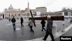 Pilgrims carry a cross as they arrive to pray in front of Saint Peter's Basilica at the Vatican in Rome, Feb. 11, 2013.