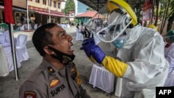 အင်ဒိုနီးရှားနိုင်ငံ Medan မြို့မှာ အင်ဒိုနီးရှား ရဲအမျိုးသားတဦးကို COVID-19 ရောဂါရှိ၊ မရှိ စစ်ဆေးပေးဖို့ swab နမူနာ ယူနေတဲ့ ကျန်းမာရေးဝန်ထမ်းတဦး။ (ဇွန် ၂၄၊ ၂၀၂၀) 