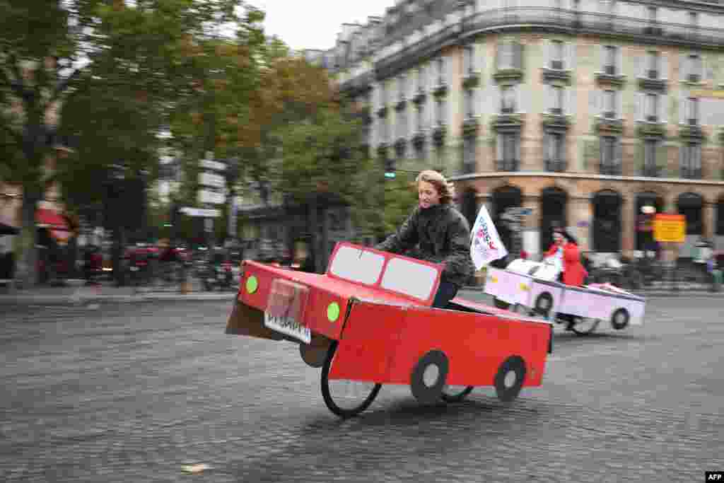 People ride a cardboard car on Place de la Bastille during a &#39;car free&#39; day in Paris, France.