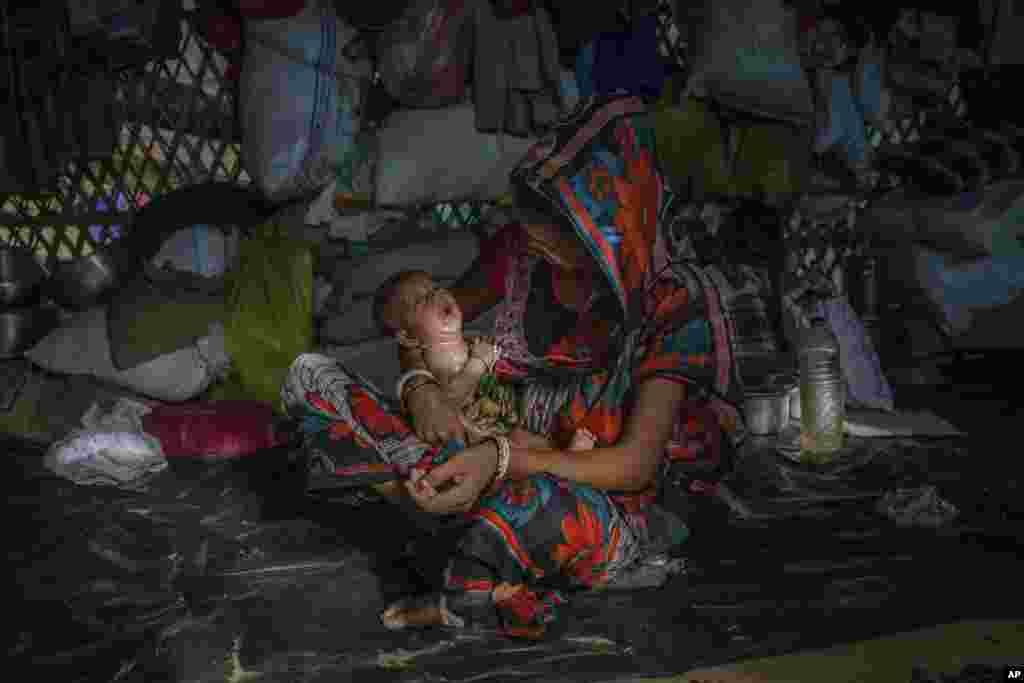 A Hindu woman, who crossed over from Myanmar into Bangladesh, holds her baby as she sits inside a refugee camp set up for Hindu refugees near Kutupalong, Bangladesh.