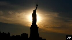 The sun rises behind the Statue of Liberty a day before the United States celebrates its independence, July 3, 2016, in Jersey City, N.J. 