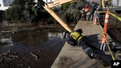 An emergency worker looks down from an overpass toward a flooded area of Highway 101 in Montecito, Calif., Jan. 11, 2018. 