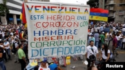 FILE - Opposition supporters rally against President Nicolas Maduro carrying a sign that reads "Venezuela is wounded in the heart with hunger, misery, corruption and dictatorship", in Caracas, Venezuela, May 10, 2017. 