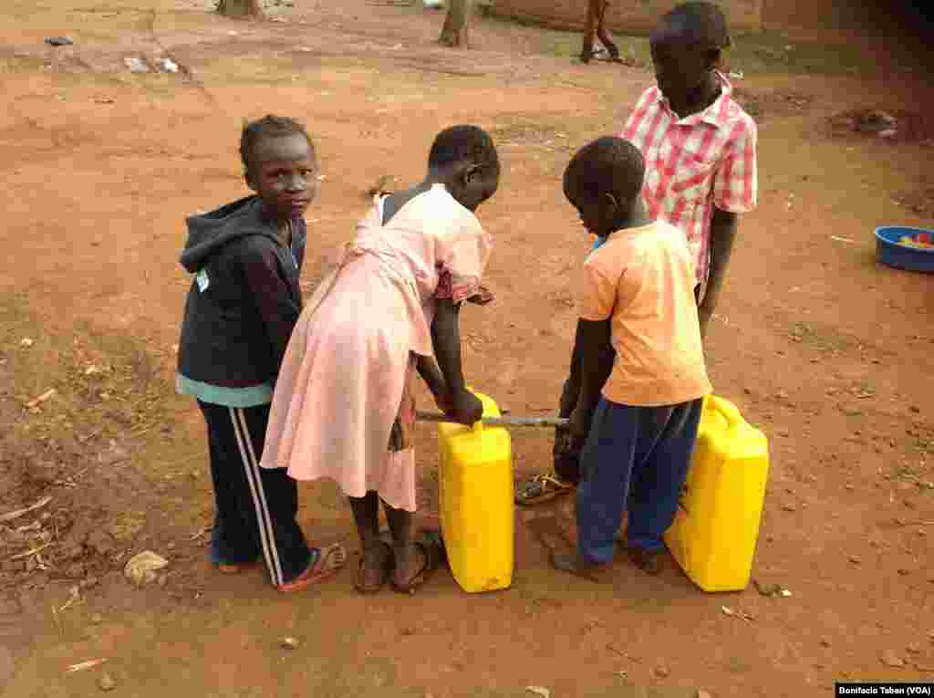 South Sudanese children at Kiryandongo settlement camp in northern Uganda struggle to carry full jerry cans of water. 