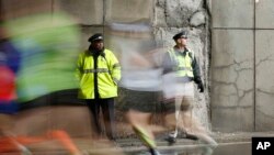 FILE - Police officers stand watch as Boston Marathon participants race along the course in Boston, April 20, 2015.