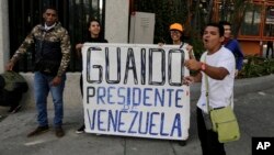 Anti-government protesters show a sign reading in Spanish "Guaido President of Venezuela" after a rally demanding the resignation of President Nicolas Maduro in Caracas, Venezuela, Jan. 23, 2019. 