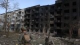 Seorang polisi Ukraina berjalan melewati bangunan tempat tinggal yang hancur, menyusul serangan artileri dan udara di desa Ocheretyne, dekat kota Avdiivka, di wilayah Donetsk, 15 April 2024.