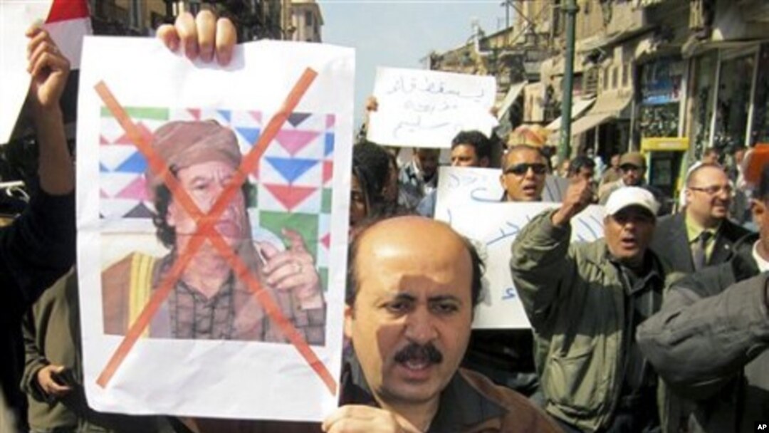 Protesters demonstrate against Libyan Leader Moammar Gadhafi, shown on placard at left, in the Mediterranean port city of Alexandria in Egypt, February 20, 2011
