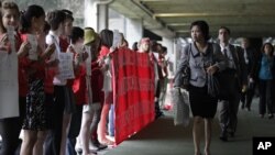 Delegates walk past activists holding signs as they arrive to the UN Conference on Sustainable Development, or Rio+20, in Rio de Janeiro, Brazil, June 20, 2012.