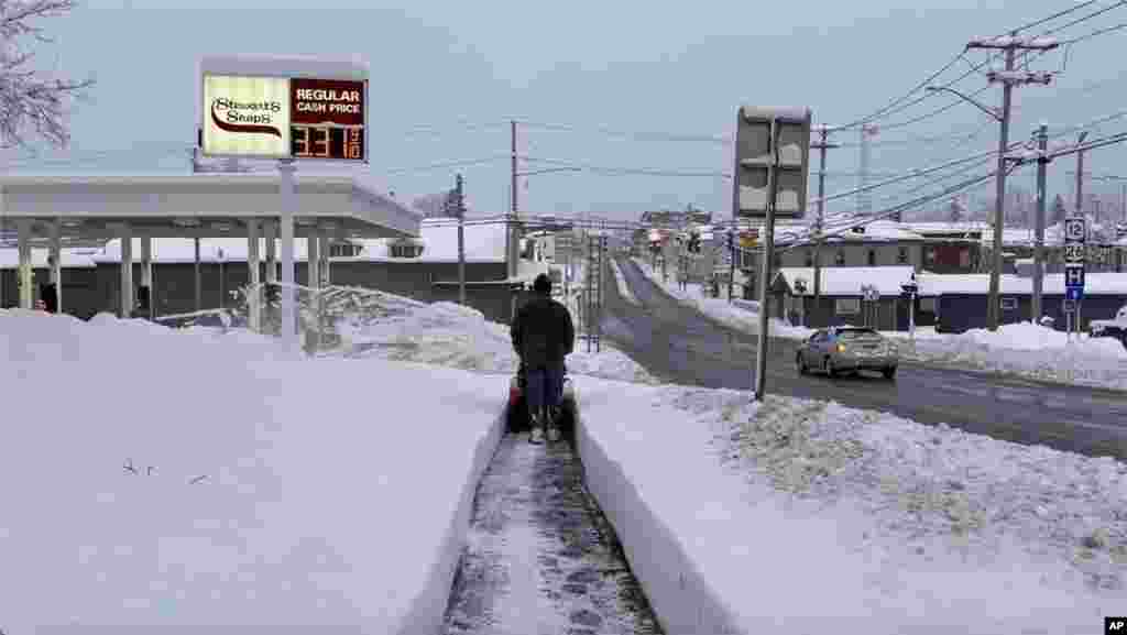 A person clears the snow from the sidewalk in Lowville, New York, Nov. 30, 2024. 