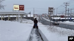 A person clears the snow from the sidewalk in Lowville, New York, Nov. 30, 2024. 