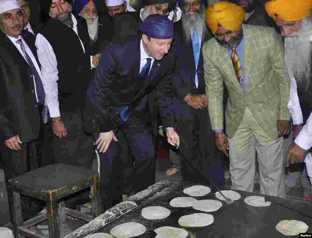 Perdana Menteri Inggris David Cameron (tengah) ikut menyiapkan roti di dapur umum pada saat melakukan kunjungan ke kuil Sikh 'Candi Emas' di kota Amritsar, India utara.