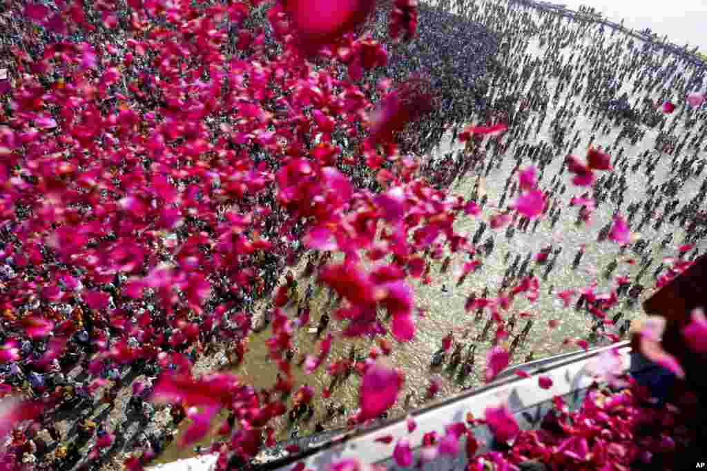 Government officials shower flower petals from a helicopter on to pilgrims gathered at the Sangam, the confluence of three rivers, the Ganges, the Yamuna and the mythical Saraswati, during the Maha Kumbh festival in Prayagraj, India.