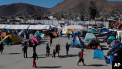 Migrants walk inside a former concert venue serving as a shelter in Tijuana, Mexico, Dec. 3, 2018.