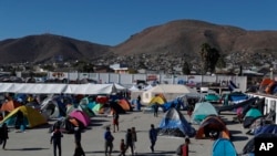 FILE - Migrants walk inside a former concert venue serving as a shelter in Tijuana, Mexico, Dec. 3, 2018.
