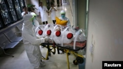 Health workers in protective suits transport a mock patient to a quarantine ward during a drill to demonstrate procedures for handling Ebola victims at a hospital in Guangzhou, China Oct. 16, 2014. 