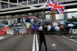 In this June 12, 2019, file photo, a protester waving the Union Jack joins other protesters using umbrellas to shield themselves outside the Legislative Council in Hong Kong.