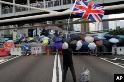 In this June 12, 2019, file photo, a protester waving the Union Jack joins other protesters using umbrellas to shield themselves outside the Legislative Council in Hong Kong.
