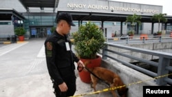 An airport police officer and a sniffer dog patrol Terminal 3 of the Ninoy Aquino International Airport in metro Manila, Sept. 1, 2014.