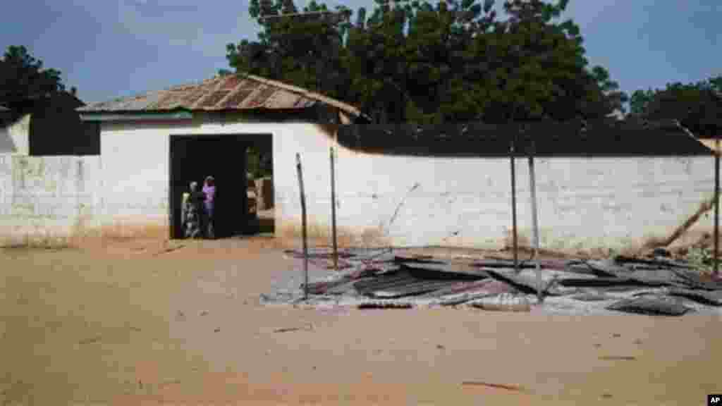 Women stand by a burnt house following an attack by Boko Haram in Benisheik.