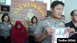 Polisi menunjukkan rentengan keping emas dalam plastik hasil sitaan kasus investasi emas ilegal. (Foto:VOA/Yudha)