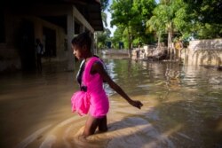 A girl wades towards her flooded home the day after the passing of Tropical Storm Laura in Port-au-Prince, Haiti, Monday, Aug. 24, 2020. Laura battered the Dominican Republic and Haiti on it's way to the U.S. Gulf Coast, where forecaster fear it…