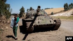 FILE - A young man walks past a destroyed tank near Debre Tabor, Ethiopia, Dec. 6, 2021. Ethiopian and Eritrean forces launched a "massive" joint offensive against the Tigray People's Liberation Front in the northern region of Tigray on Sept. 1, 2022, the