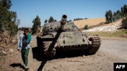 FILE - A young man walks past a destroyed tank near Debre Tabor, Ethiopia, Dec. 6, 2021.