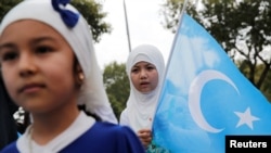 FILE - An ethnic Uyghur girl holds an East Turkestan flag during a protest against China, in Istanbul, Turkey, Aug. 31, 2022.