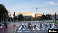 Migrantes cruzan Massachusetts Avenue hacia Union Station, cerca del Capitolio de EEUU, en Washington DC, después de completar un viaje en autobús desde Texas, el 30 de julio de 2022.