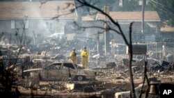 Firefighters survey homes on Wakefield Avenue destroyed by the Mill Fire, Sept. 3, 2022, in Weed, Calif.