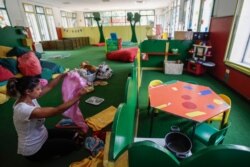 A worker tidies up the playroom in the 'La Giostra Nel Parco' nursery school in Milan, northern Italy, Aug. 27, 2020, ahead of reopening.