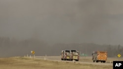 Fire trucks drive toward smoke from a wildfire near Fort McMurray, Alberta, Canada, May 8, 2016. Officials said Sunday they were hoping to get a “death grip” on the blaze amid cooler temperatures.