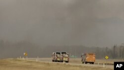 Fire trucks drive toward smoke from a wildfire near Fort McMurray, Alberta, Canada, May 8, 2016. Officials said Sunday they were hoping to get a “death grip” on the blaze amid cooler temperatures.