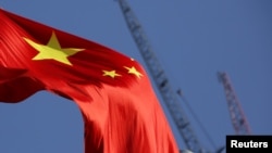 China's national flag is seen in front of cranes on a construction site at a commercial district in Beijing, China, Jan. 26, 2016. 