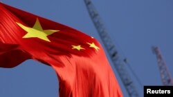 China's national flag is seen in front of cranes on a construction site at a commercial district in Beijing, China, Jan. 26, 2016. 