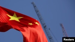 FILE - China's national flag is seen in front of cranes on a construction site at a commercial district in Beijing, China, Jan. 26, 2016. 