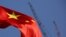 FILE - China's national flag is seen in front of cranes on a construction site at a commercial district in Beijing, China, Jan. 26, 2016. 