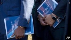 Members of the Congressional Black Caucus hold pamphlets that read "We Have a Lot to Lose" as they speak to members of the media after meeting with President Donald Trump in the Cabinet Room of the White House, March 22, 2017, in Washington. Caucus members have a not accepted an invitation for a second meeting with Trump.