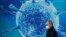 A man wearing a protective face mask walks past an illustration of a virus outside a regional science centre. (REUTERS/Phil Noble)