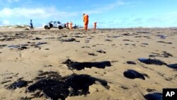 Workers remove oil from Viral Beach, in Aracaju, Brazil, Oct. 7, 2019. The oil sludge has now reached 61 municipalities in nine Brazilian states, contaminating over 130 beaches.